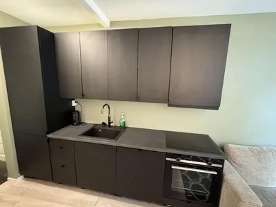 a kitchen with black cabinets and a sink at Perfect central apartment Trondheim in Trondheim
