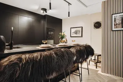 a kitchen with black cabinets and a table with fur chairs at Central apartment building in Bergen