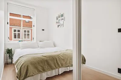 a white bedroom with a bed and a window at Central apartment building in Bergen