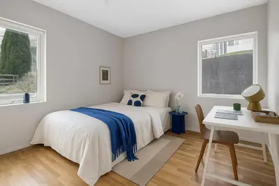 a bedroom with a bed and a desk and two windows at Cozy Apartment near City Centre in Bergen