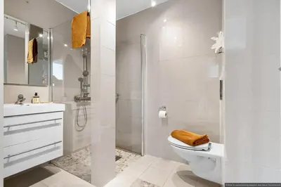 a white bathroom with a toilet and a shower at Cozy Apartment near City Centre in Bergen