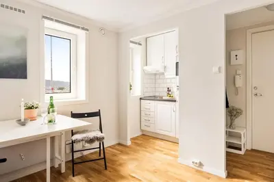 a kitchen with white cabinets and a white table and chairs at Appartment Bergen, Skansen in Bergen