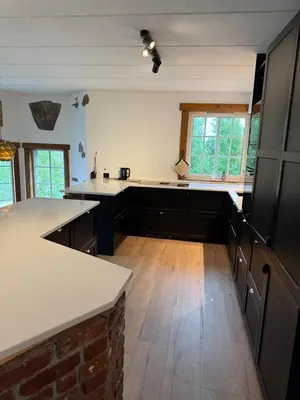 a kitchen with white counter tops and wooden floors at Haven Fortress in Lii