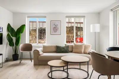 a living room with a couch and tables and windows at City Center, Light & Modern Apartment in Bergen