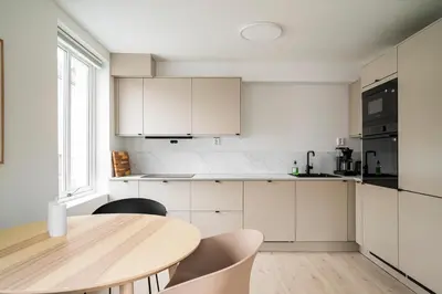 a kitchen with white cabinets and a wooden table at City Center, Light & Modern Apartment in Bergen
