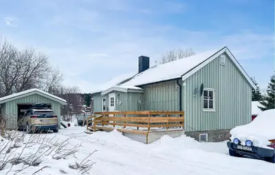 a green house in the snow with a car parked in front at Cozy Home In Sparbu With Wifi in Sparbu