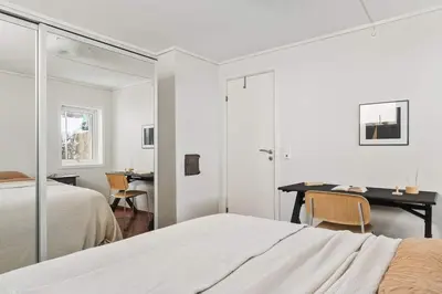 a white bedroom with a desk and a bed at Bright and cozy 2-bedroom apartment in Bergen