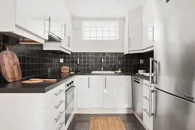 a kitchen with white cabinets and a stainless steel refrigerator at Bright and cozy 2-bedroom apartment in Bergen