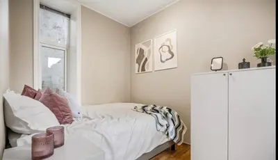 a white bedroom with a bed and a window at Central and cozy apartment in Bergen City Center in Bergen