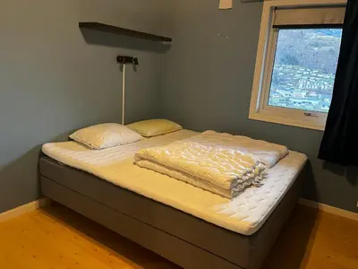 a bed with a blanket on it in a room with a window at Apartment Stedjeåsen 70 in Sogndal