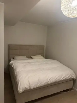 a bedroom with a bed with a white bedspread at Stor og moderne leilighet ved råstølen bybanestopp in Bergen