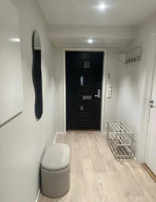 a hallway with a black door and a stool in front of it at Stor og moderne leilighet ved råstølen bybanestopp in Bergen