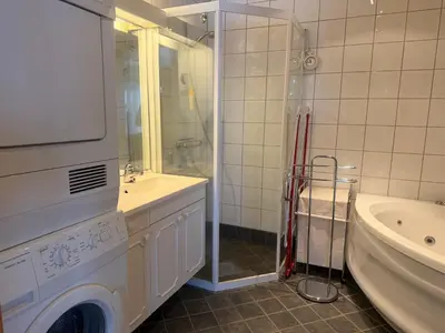 a bathroom with a washing machine next to a sink and a tub at Koselig Leilighet Med Flott Utsikt in Beitostøl