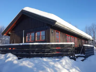 a log cabin with a snow covered roof and a bench at Familievennlig Hytte Rett Ved Sentrum in Beitostøl