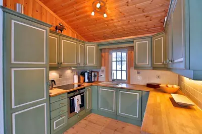 a kitchen with green cabinets and a wooden ceiling at Relax And Unwind At Slettero-A Cozy Family Getaway in Beitostøl