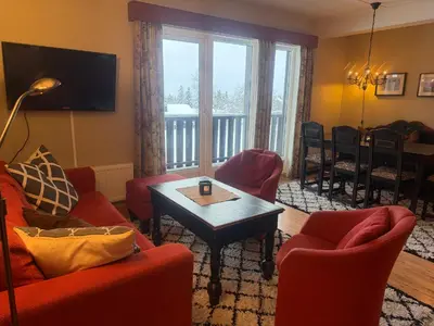 a living room with red furniture and a balcony at 3-Roms Leilighet Nær Alle Beitostølens Fasiliteter in Beitostøl