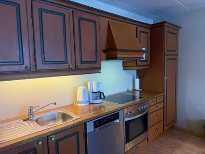 a kitchen with wooden cabinets and a stainless steel sink at 3-Roms Leilighet Nær Alle Beitostølens Fasiliteter in Beitostøl