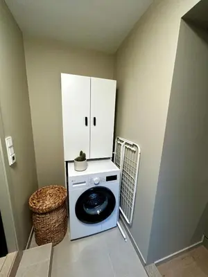 a washing machine in a room with a white cabinet at Fantastic village apartment in Bergen in Bergen