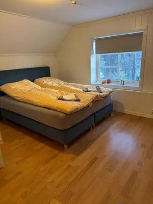 a bedroom with a bed with a window and wooden floors at Huset i den lykkelige gaten in Elverum
