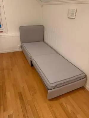 a small bed in a room with a wooden floor at Huset i den lykkelige gaten in Elverum