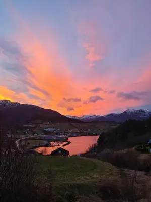 a sunset over a body of water with mountains at Leilighet i paradisbukta in Torvikbukt