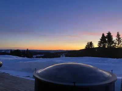 a hot tub in the snow at sunset at Mountain cabin in Lillehammer in Lillehammer