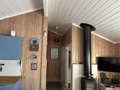 a room with a wood paneled wall with a stove at Mountain cabin in Lillehammer in Lillehammer