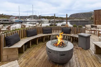a patio with a fire pit and benches on a dock at Kuringen Brygge Hotel and Restaurant in Refsnes