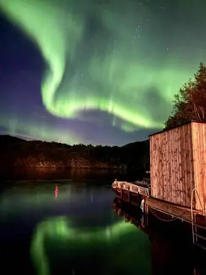 an aurora over a body of water with a dock at Kuringen Brygge Hotel and Restaurant in Refsnes