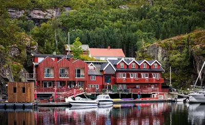 a large red building with boats docked in a body of water at Kuringen Brygge Hotel and Restaurant in Refsnes