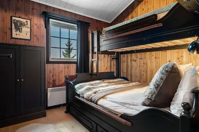 a bedroom with a large bed in a room with wooden walls at Trysilfjell hytteomrade 589 in Hovi