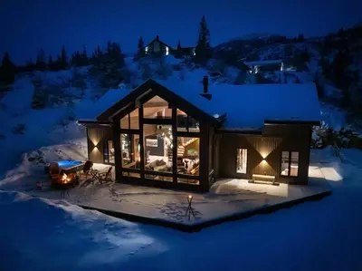 a cabin in the snow at night at FJELLRO Private Alpine Lodge Høgevarde in Flå