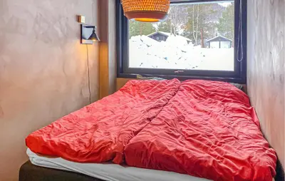 a bed with a red comforter in front of a window at Amazing Apartment In Bjorli With Wifi in Bjorli