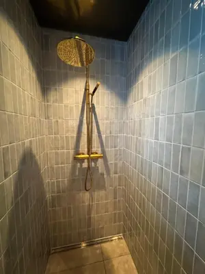 a bathroom with a shower with blue tiles at Gunhild-stugu