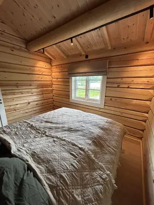 a large bed in a wooden room with a window at Gunhild-stugu