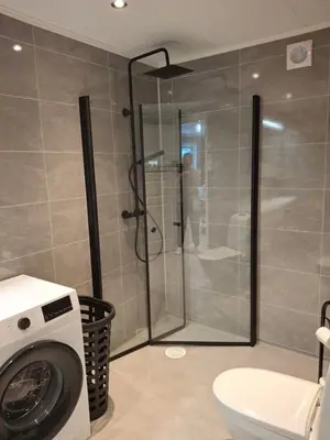 a bathroom with a shower and a washing machine at Bjørgebu Camping AS in Nord-Fron