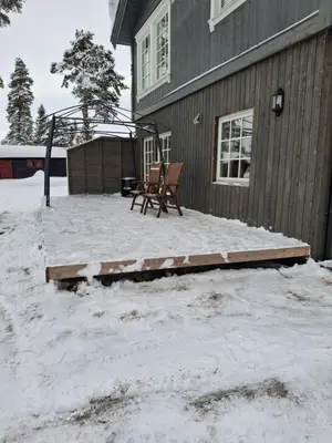 a patio with two chairs in the snow next to a house at Bjørgebu Camping AS in Nord-Fron