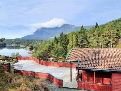 a house with a wooden deck next to a lake at Holiday Home Ein Traumstandort by Interhome in Hebnes