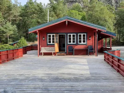 a red cabin with a bench on a wooden boardwalk at Holiday Home Ein Traumstandort by Interhome in Hebnes