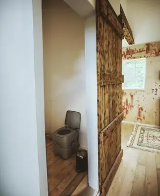 a bathroom with a toilet and a wooden door at Romantic Getaway Hot Tub, Cinema & View in Stange