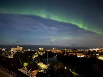 an aurora in the sky over a city at night at Modern 3-bedroom apartment with a view in Trondheim