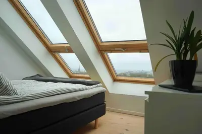 a attic room with two windows and a potted plant at Modern 3-bedroom apartment with a view in Trondheim