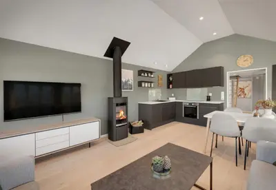 a living room with a tv and a kitchen with a fireplace at Exclusive mountain cabin - Panoramic views in Vossevangen