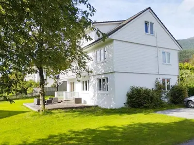 a white house with a tree in the yard at Women Only - Guestroom in centre of Førde town in Førde