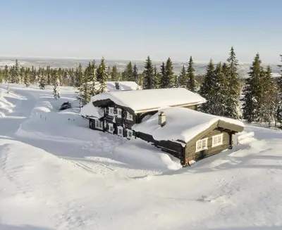 a house covered in snow with trees in the background at Cabin at Fageråsen - 4 roomed family cabin for skiing in Trysil in Trysil