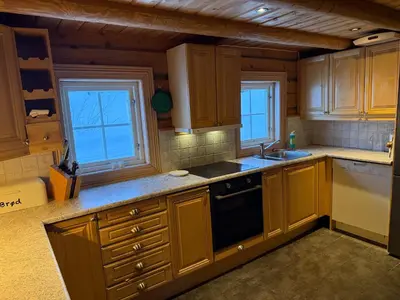 a kitchen with wooden cabinets and a sink and two windows at Cabin at Fageråsen - 4 roomed family cabin for skiing in Trysil in Trysil