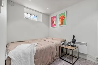 a white bedroom with a bed and a side table at Spacious 3 Bedroom Basement Apartment with Parking, Close to Trondheim City Center in Trondheim