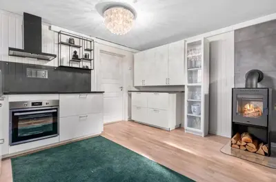 a kitchen with white cabinets and a fireplace at Spacious 3 Bedroom Basement Apartment with Parking, Close to Trondheim City Center in Trondheim