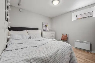 a white bedroom with a large bed and a dresser at Spacious 3 Bedroom Basement Apartment with Parking, Close to Trondheim City Center in Trondheim