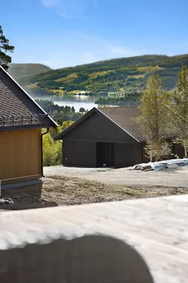 a black building with a lake in the background at New and great cabin at the foot of Norefjell in Noresund